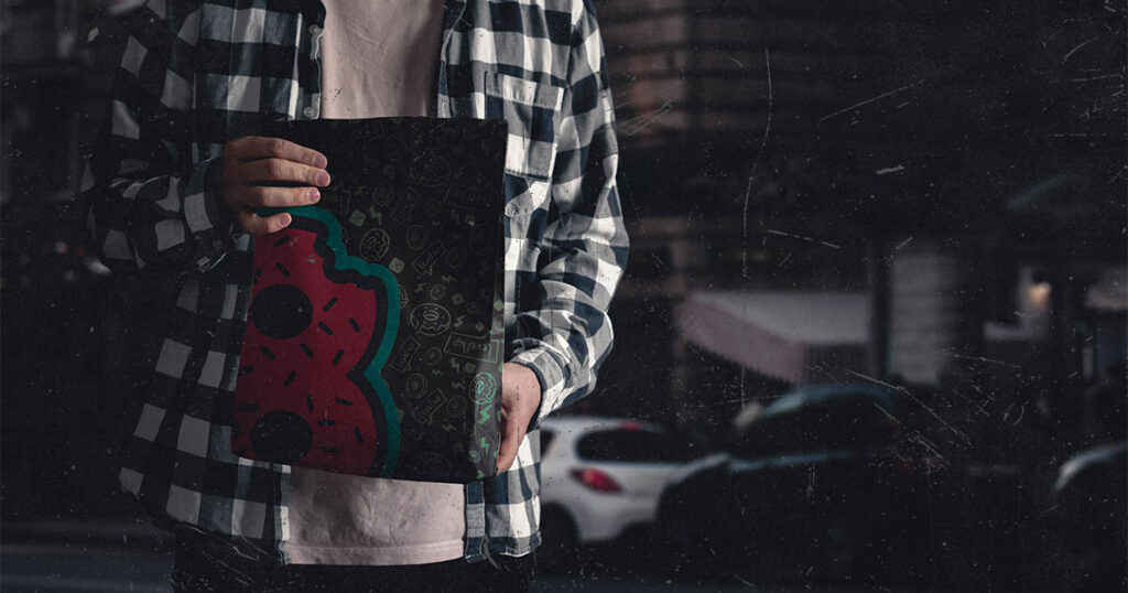Person holding 8Bite branded to-go bag featuring bold donut “8” logo with graphic food icon pattern, in urban nighttime setting