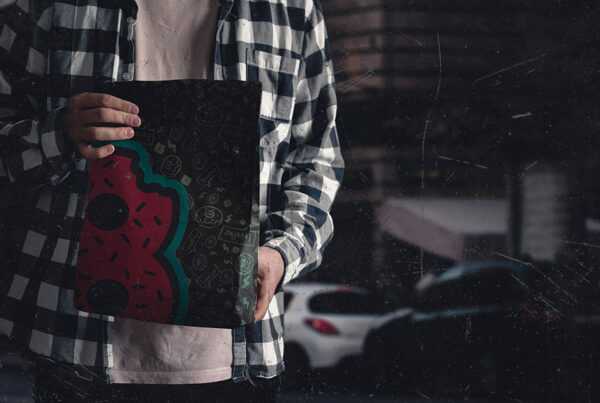 Person holding 8Bite branded to-go bag featuring bold donut “8” logo with graphic food icon pattern, in urban nighttime setting